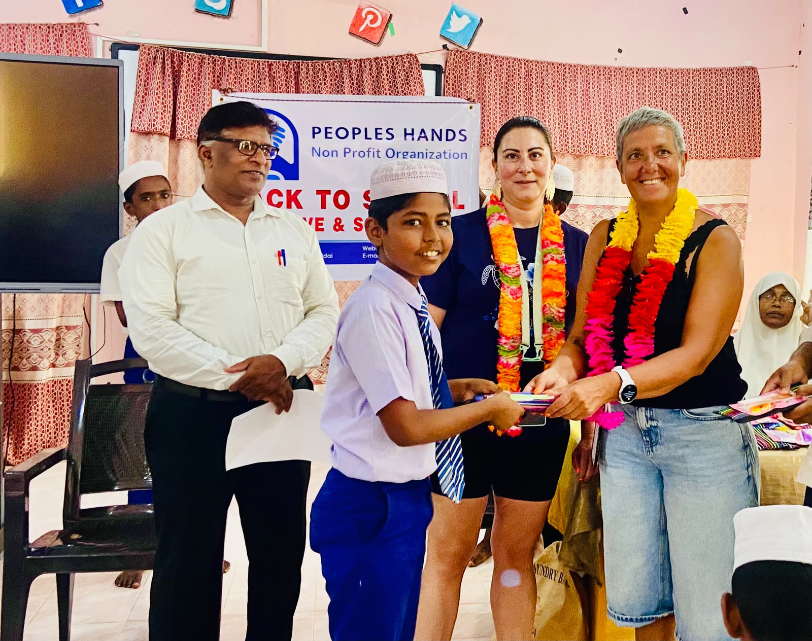 Amandine from France handing a school kit to a student at T/Mohamadiya Vidyalayam, Iqbalnagar, Kuchchaveli